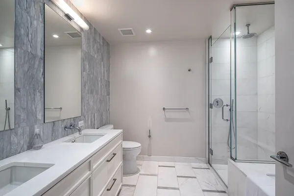 a bathroom with a double vanity sink toilet and shower