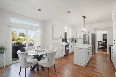 a view of a dining room and livingroom with furniture wooden floor a chandelier