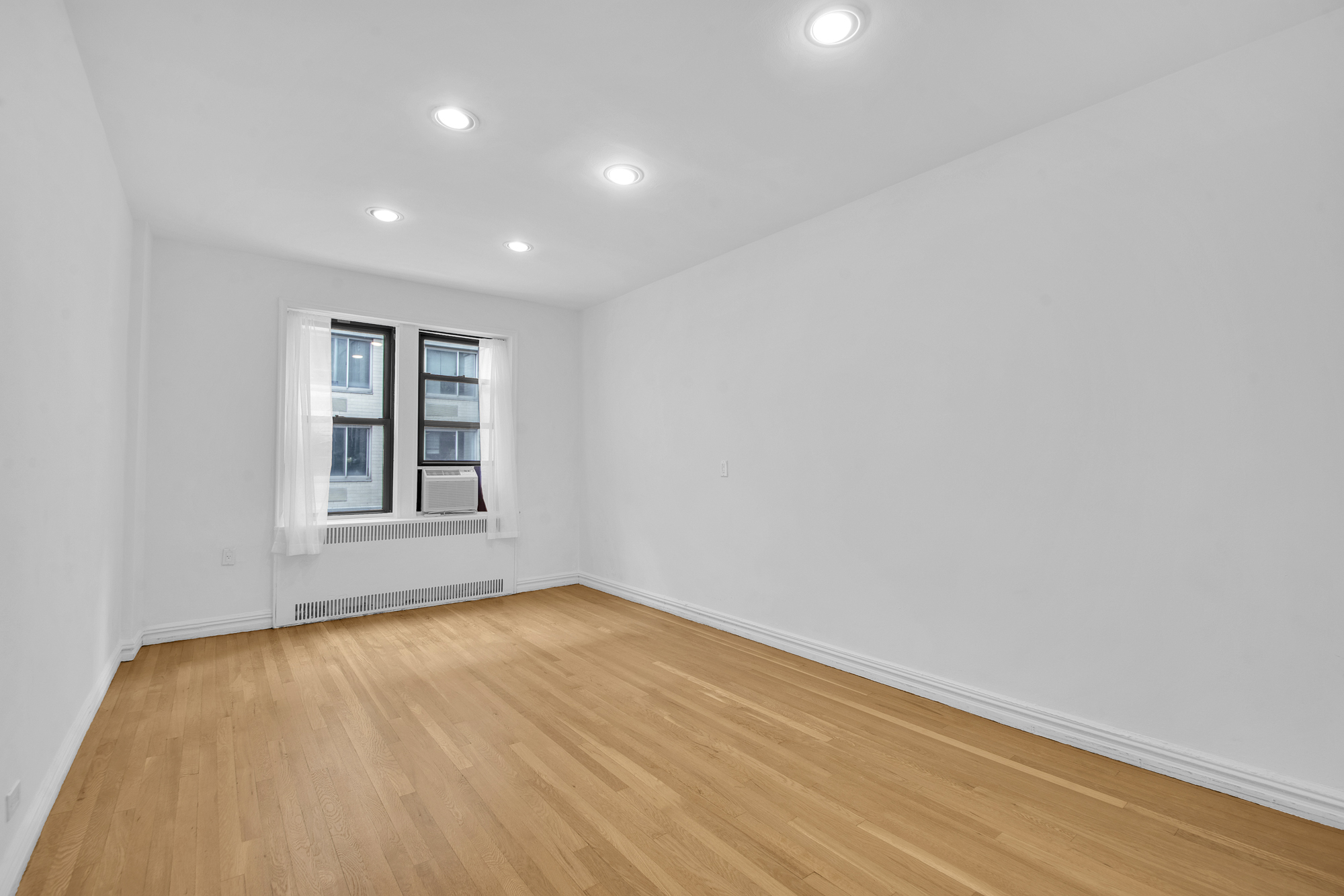 225 West 25th Street, Unit 5K Manhattan, NY 10001 - Photo 9 of 17 a view of an empty room with wooden floor and a window