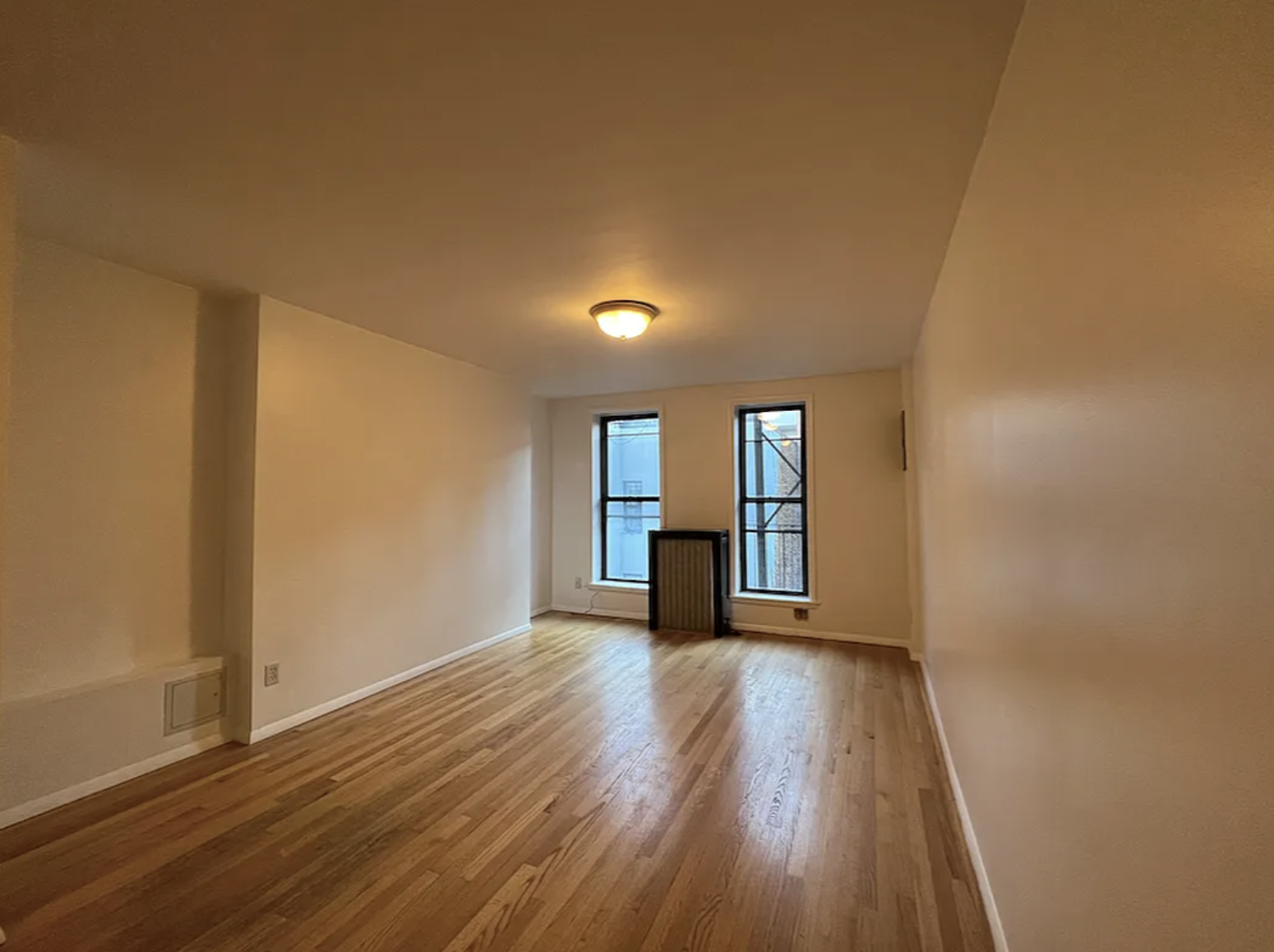446 West 46th Street, Unit 12 Manhattan, NY 10036 - Photo 3 of 18 a view of empty room with wooden floor and fan