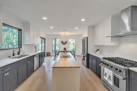 a large kitchen with stainless steel appliances granite countertop a lot of counter space and wooden floors