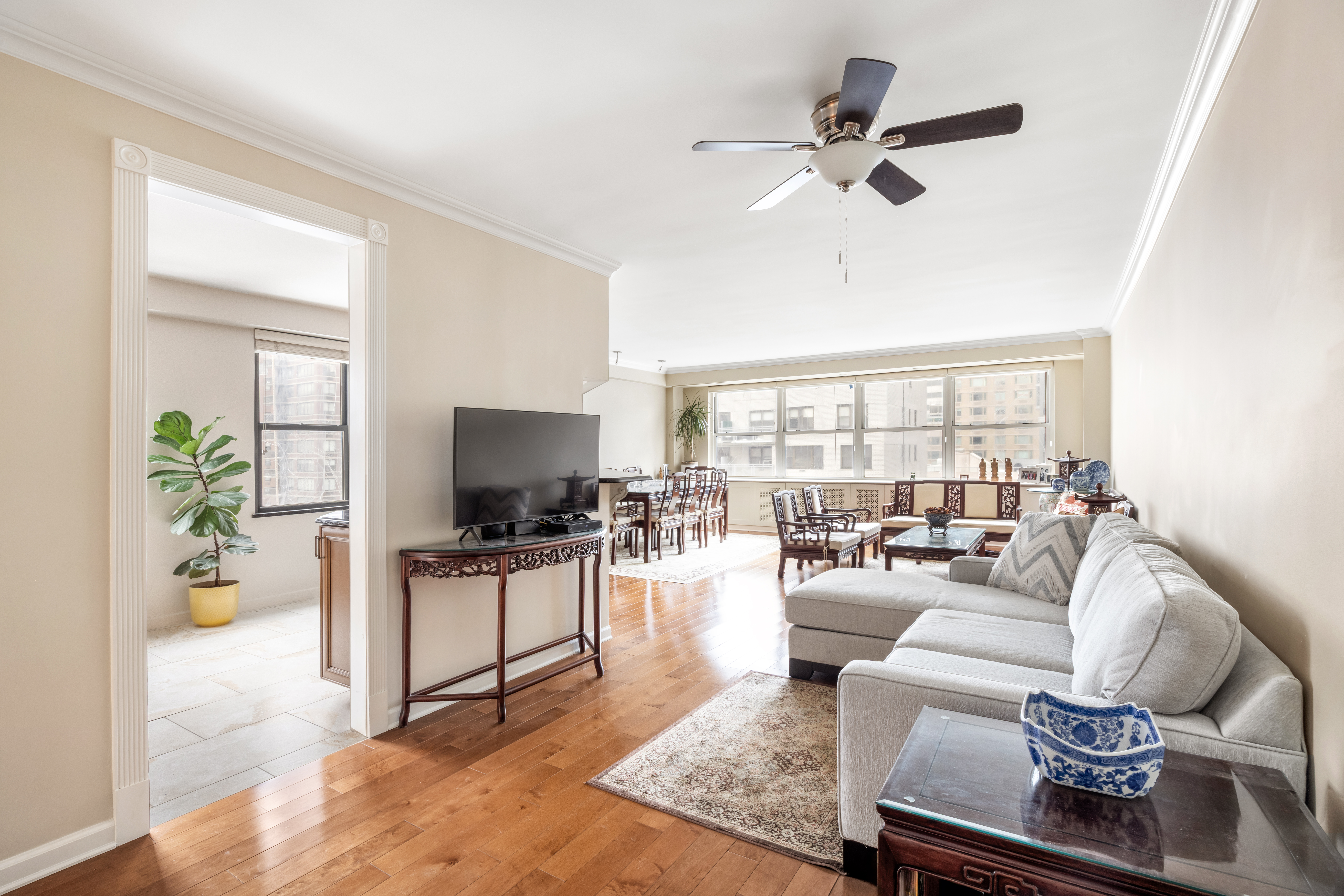399 East 72nd Street, Unit 15A Manhattan, NY 10021 - Photo 3 of 10 a living room with furniture a flat screen tv and a floor to ceiling window