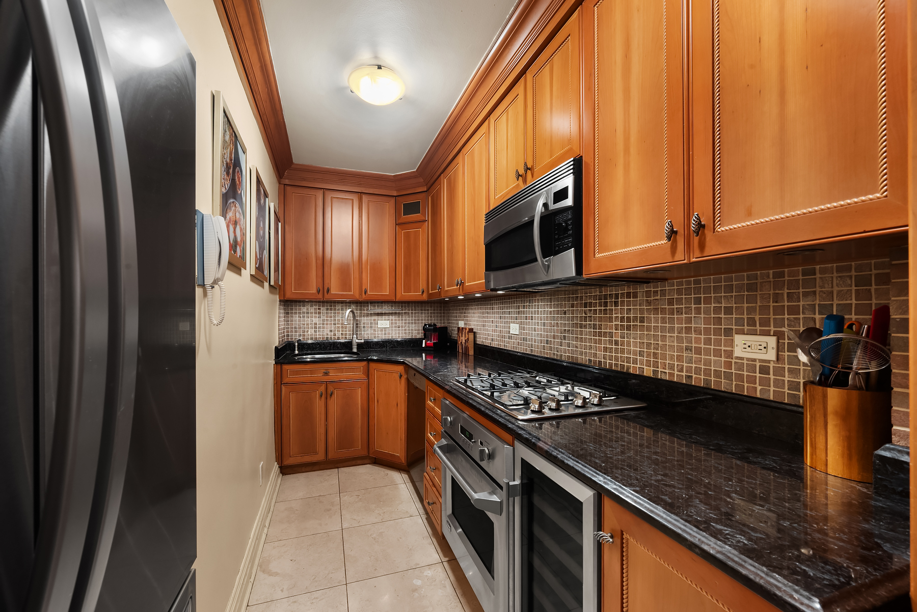 301 East 62nd Street, Unit 2K Manhattan, NY 10065 - Photo 7 of 9 a kitchen with stainless steel appliances granite countertop a stove a sink and a microwave