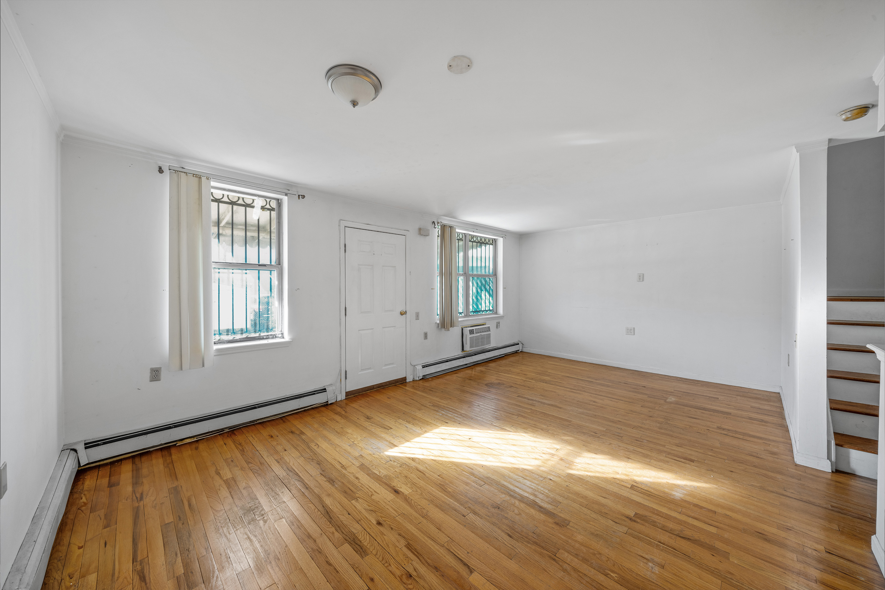 2028 Bergen Street, Unit 1 Brooklyn, NY 11233 - Photo 2 of 9 an empty room with wooden floor and windows