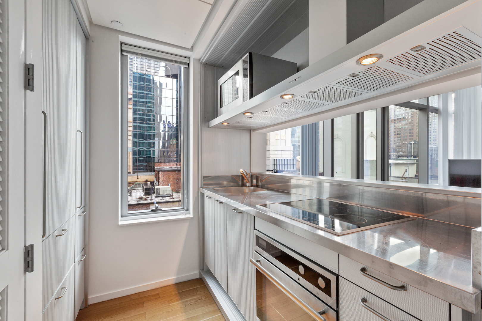 18 West 48th Street, Unit 17C Manhattan, NY 10036 - Photo 2 of 5 a kitchen with stainless steel appliances granite countertop a sink and a large window