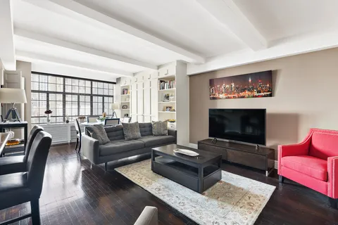 a living room with furniture a rug a flat screen tv and a large window