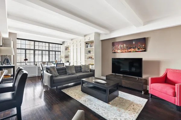 a living room with furniture a rug a flat screen tv and a large window