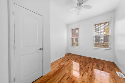 a view of empty room with wooden floor and fan
