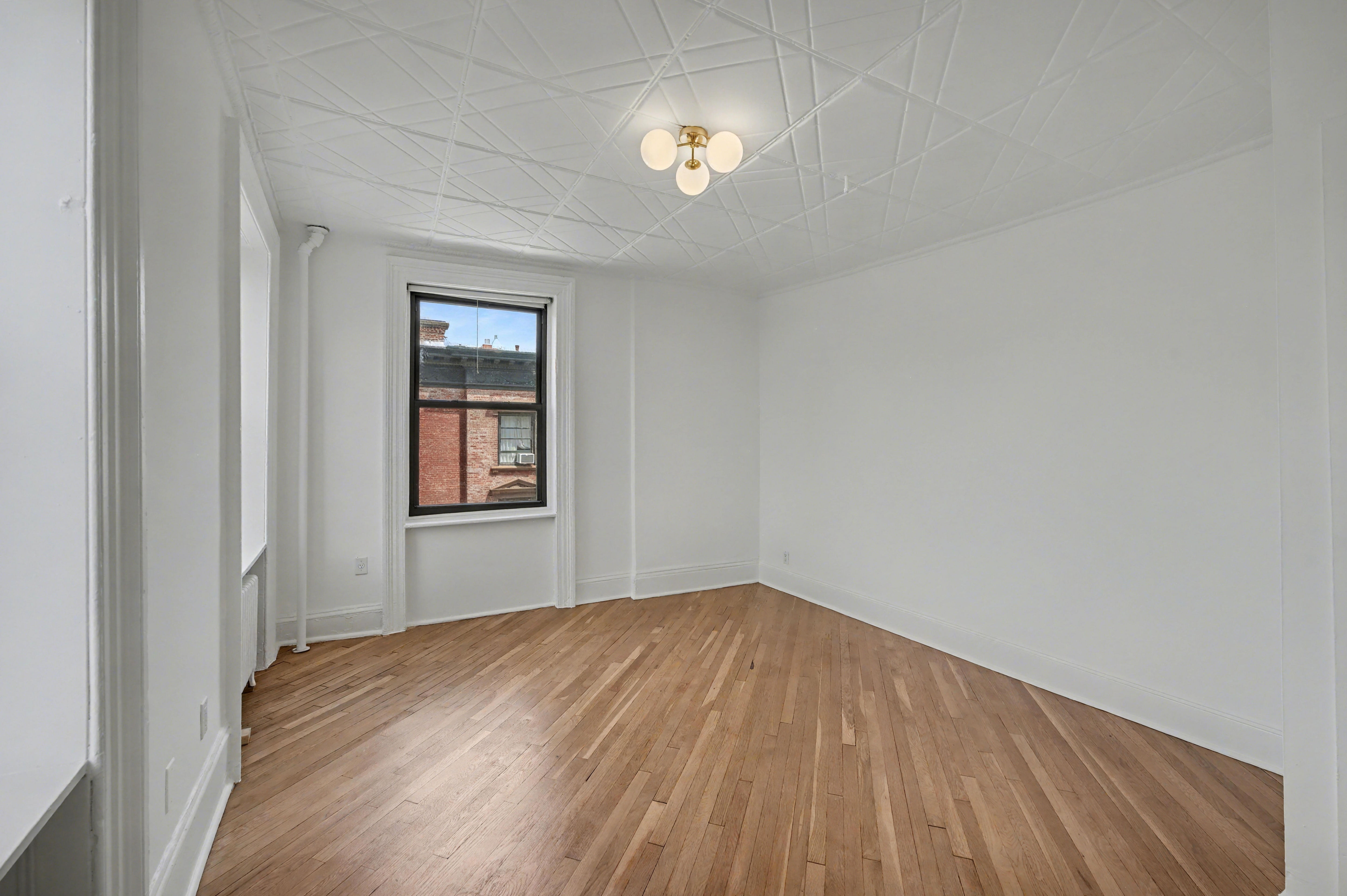261 Clinton Street, Unit 3 Brooklyn, NY 11201 - Photo 7 of 12 a view of empty room with wooden floor and fan