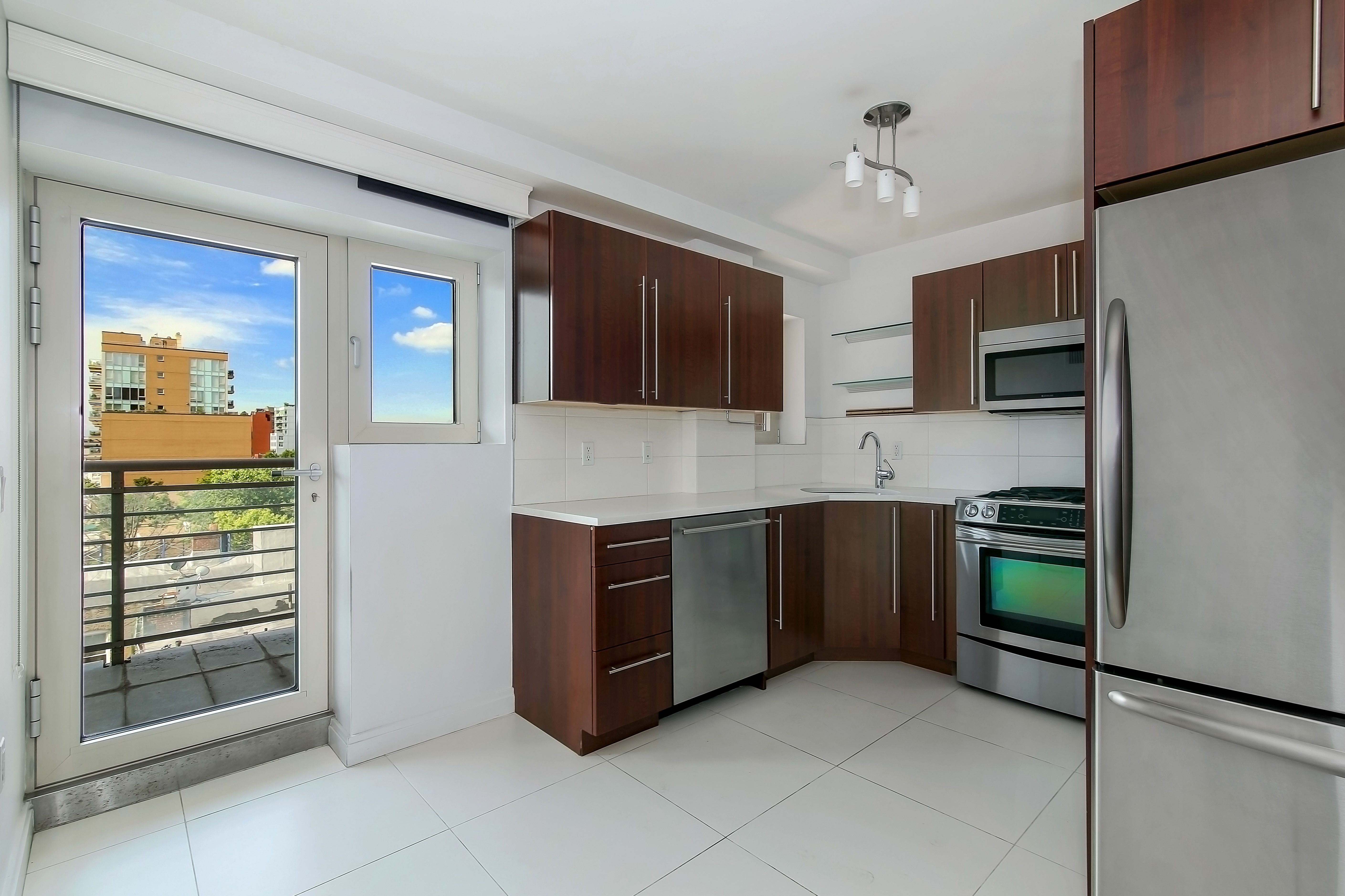 302 2nd Street, Unit 9L Brooklyn, NY 11215 - Photo 3 of 12 a large kitchen with stainless steel appliances granite countertop a stove and a microwave