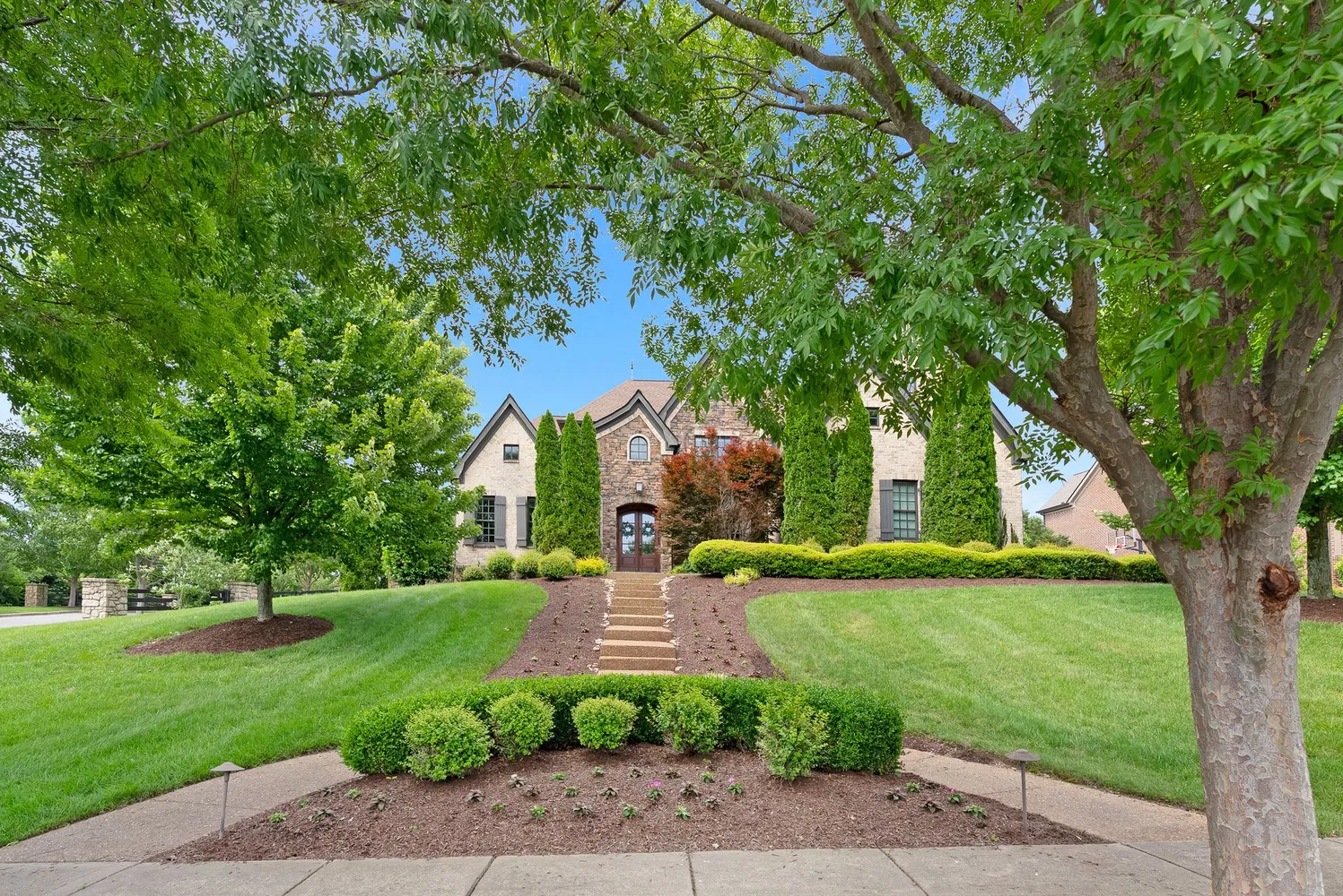 a view of a park with large trees and a barn