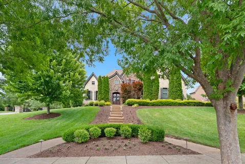 a view of a park with large trees and a barn