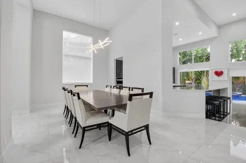 a view of a dining room with furniture a chandelier and a window