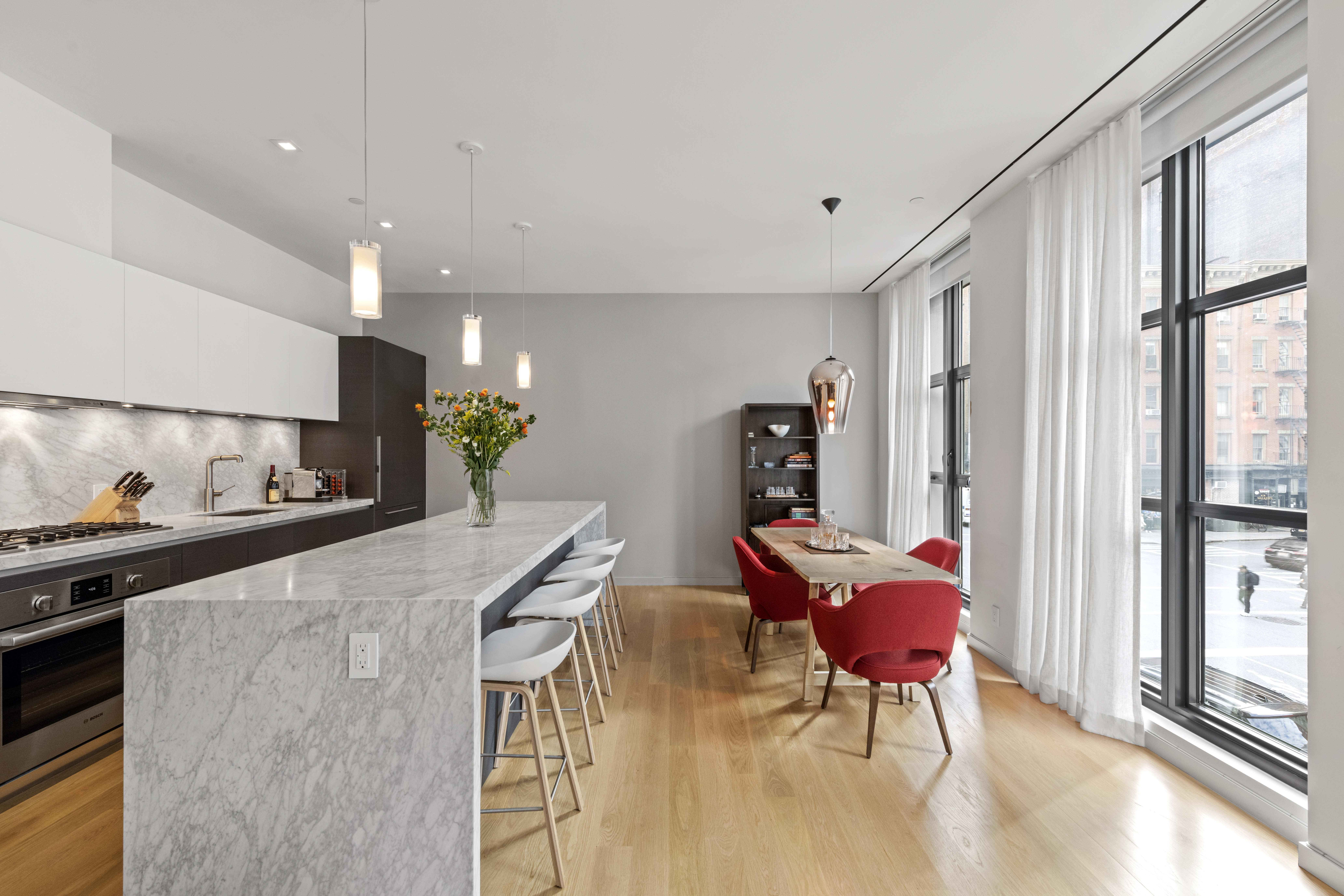 11 North Moore Street, Unit 2B Manhattan, NY 10013 - Photo 4 of 12 a kitchen with stainless steel appliances kitchen island granite countertop a refrigerator a stove a dining table and chairs with wooden floor