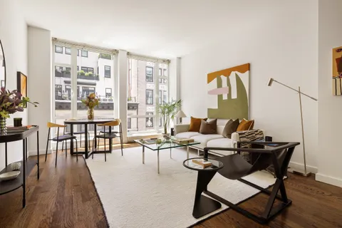 a living room with furniture wooden floor and a floor to ceiling window