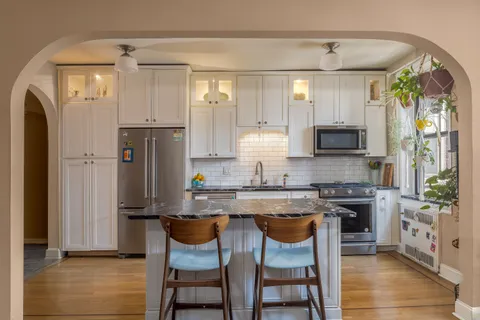 a kitchen with stainless steel appliances granite countertop a refrigerator a stove and white cabinets with wooden floor