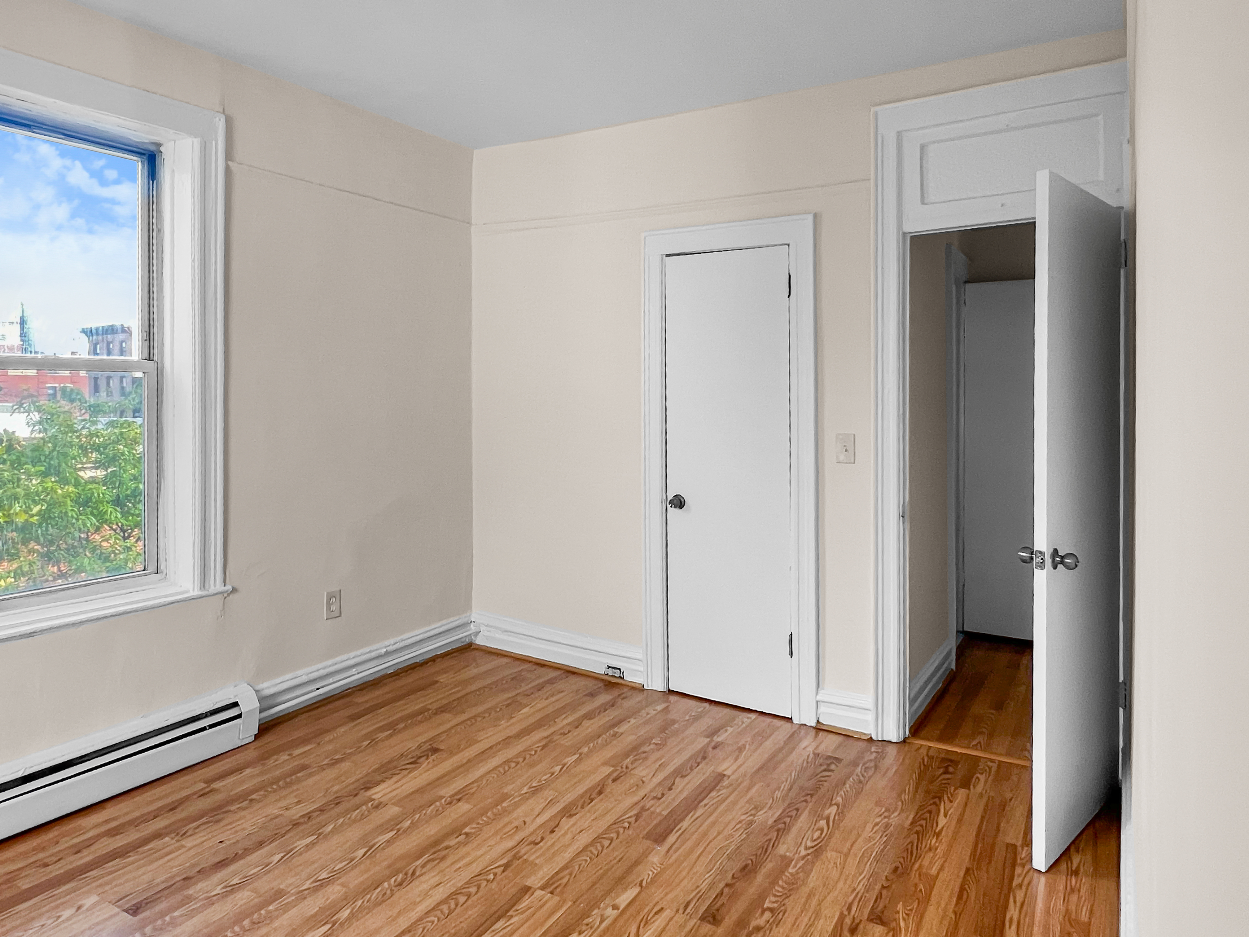 35-19 Broadway, Unit 3 Queens, NY 11106 - Photo 4 of 11 a view of an empty room with wooden floor and a window