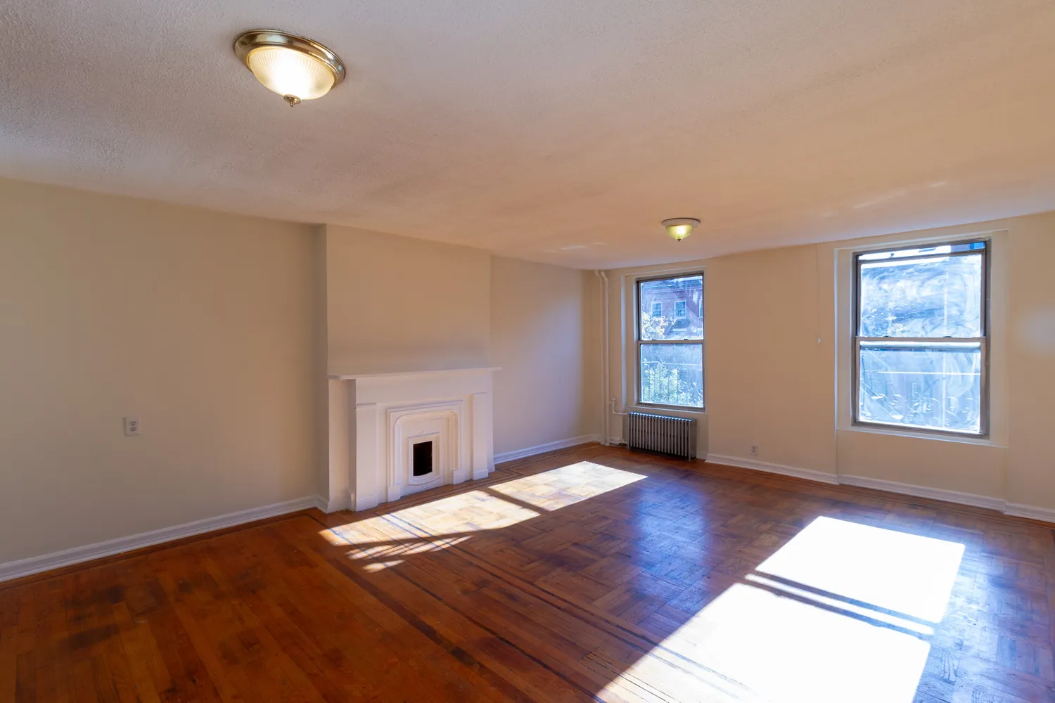 a view of an empty room with window and wooden floor