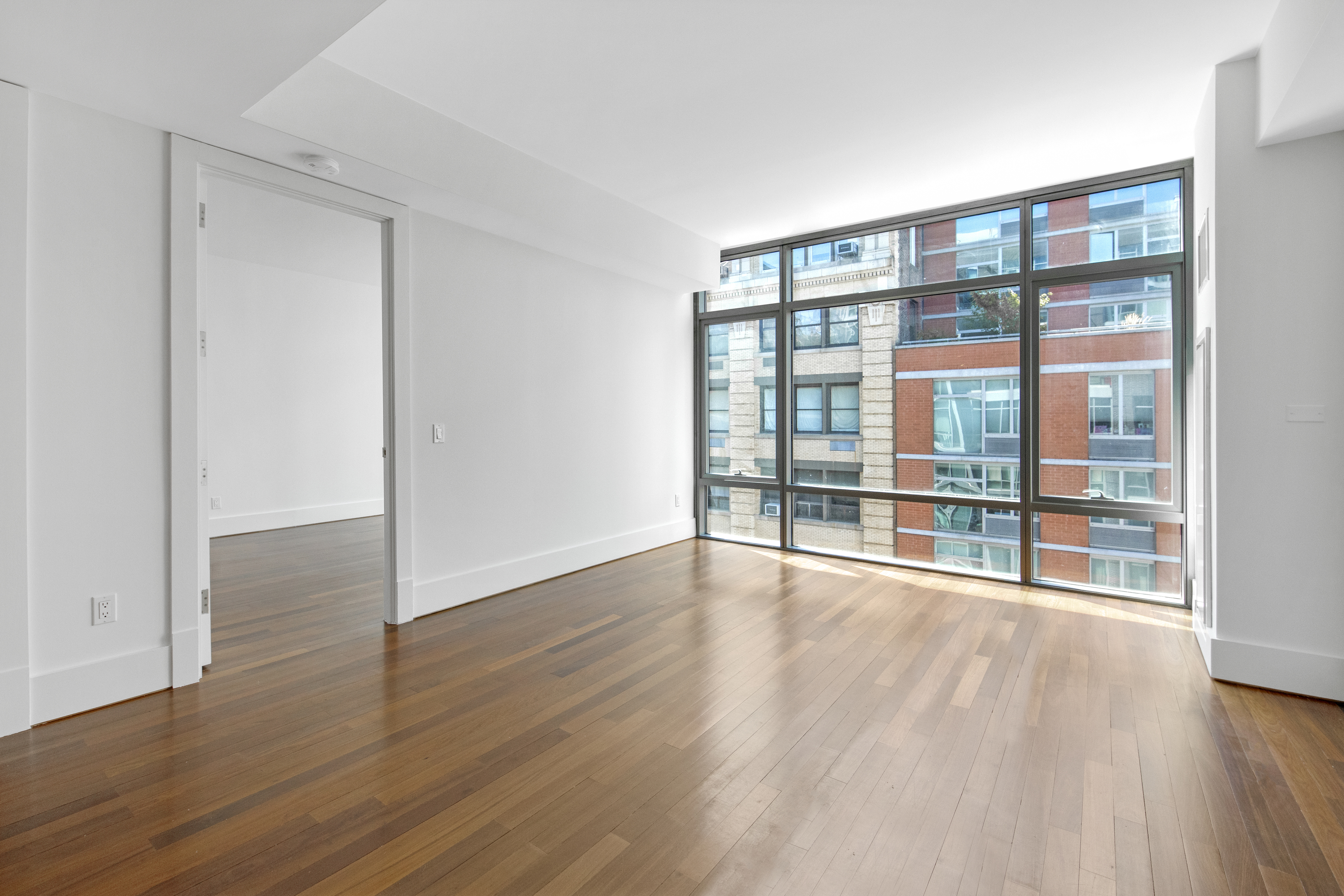 165 West 18th Street, Unit 8B Manhattan, NY 10011 - Photo 1 of 9 a view of an empty room with wooden floor and a window