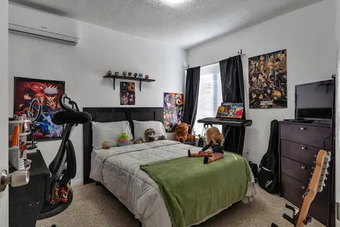 a bedroom with bed a flat tv screen and dresser