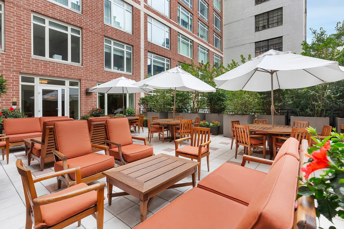 205 East 85th Street, Unit 16H Manhattan, NY 10028 - Photo 11 of 14 a view of a patio with a dining table and chairs under an umbrella