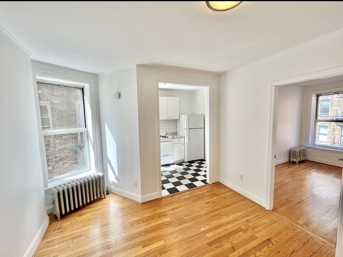 a view of an empty room with glass door and wooden floor