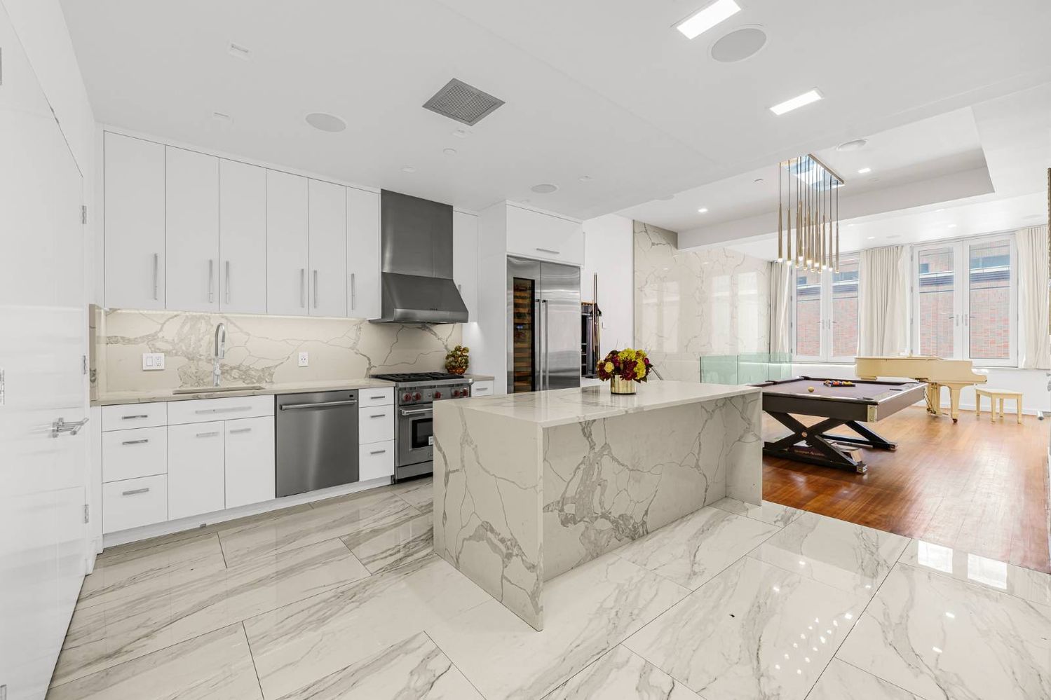 a large white kitchen with a stove a sink dishwasher and a refrigerator with wooden floor