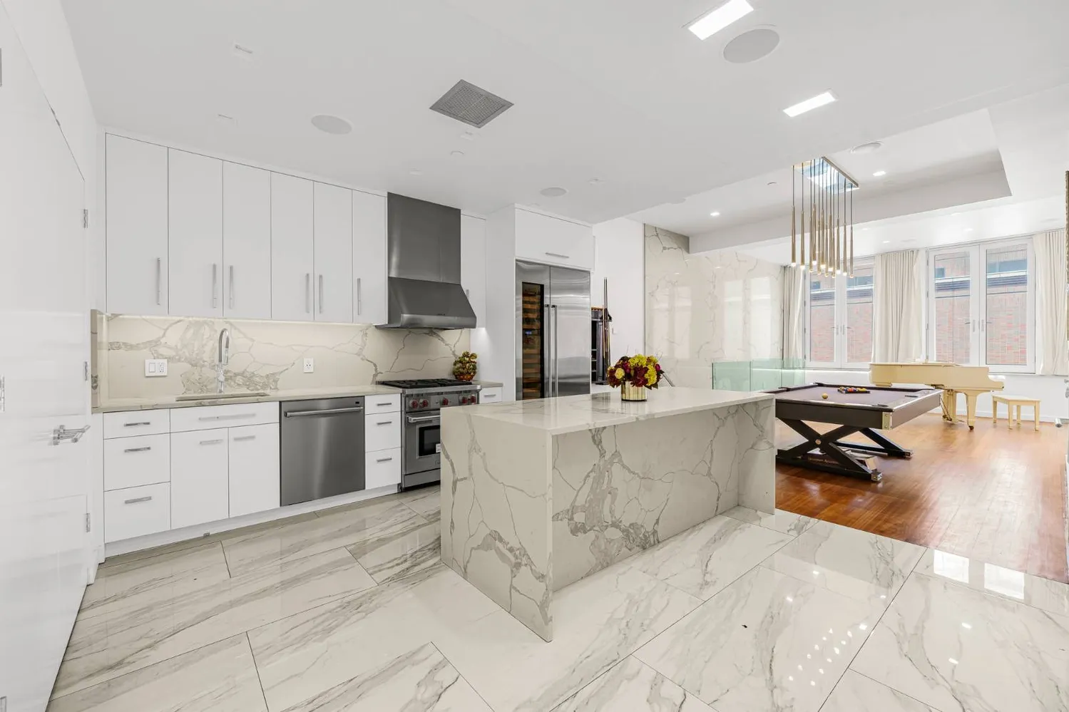 a large white kitchen with a stove a sink dishwasher and a refrigerator with wooden floor