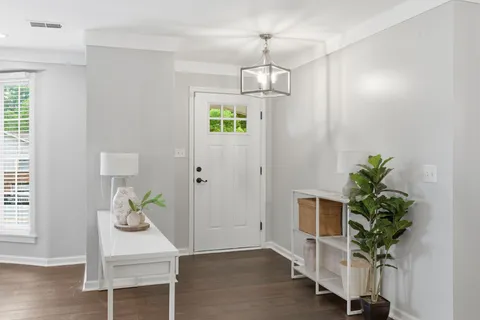 a view of a hallway with wooden floor and a chandelier