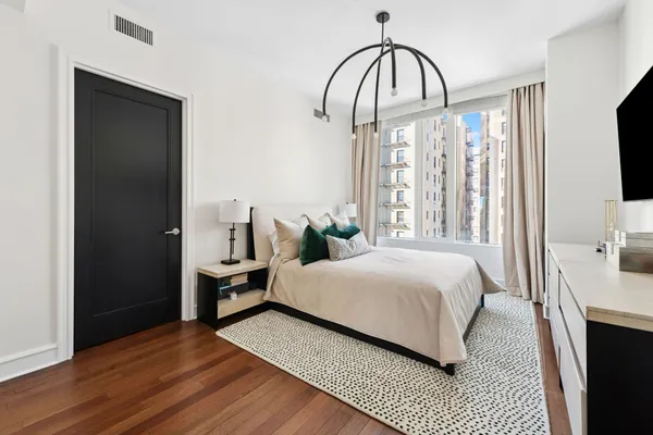 a bedroom with a bed and a flat tv screen on dresser