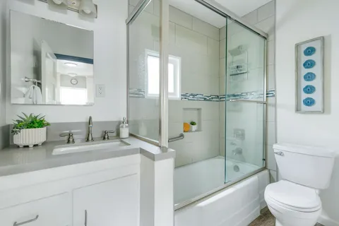 a bathroom with a granite countertop sink toilet and shower