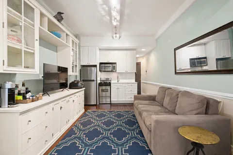a living room with stainless steel appliances furniture and a kitchen