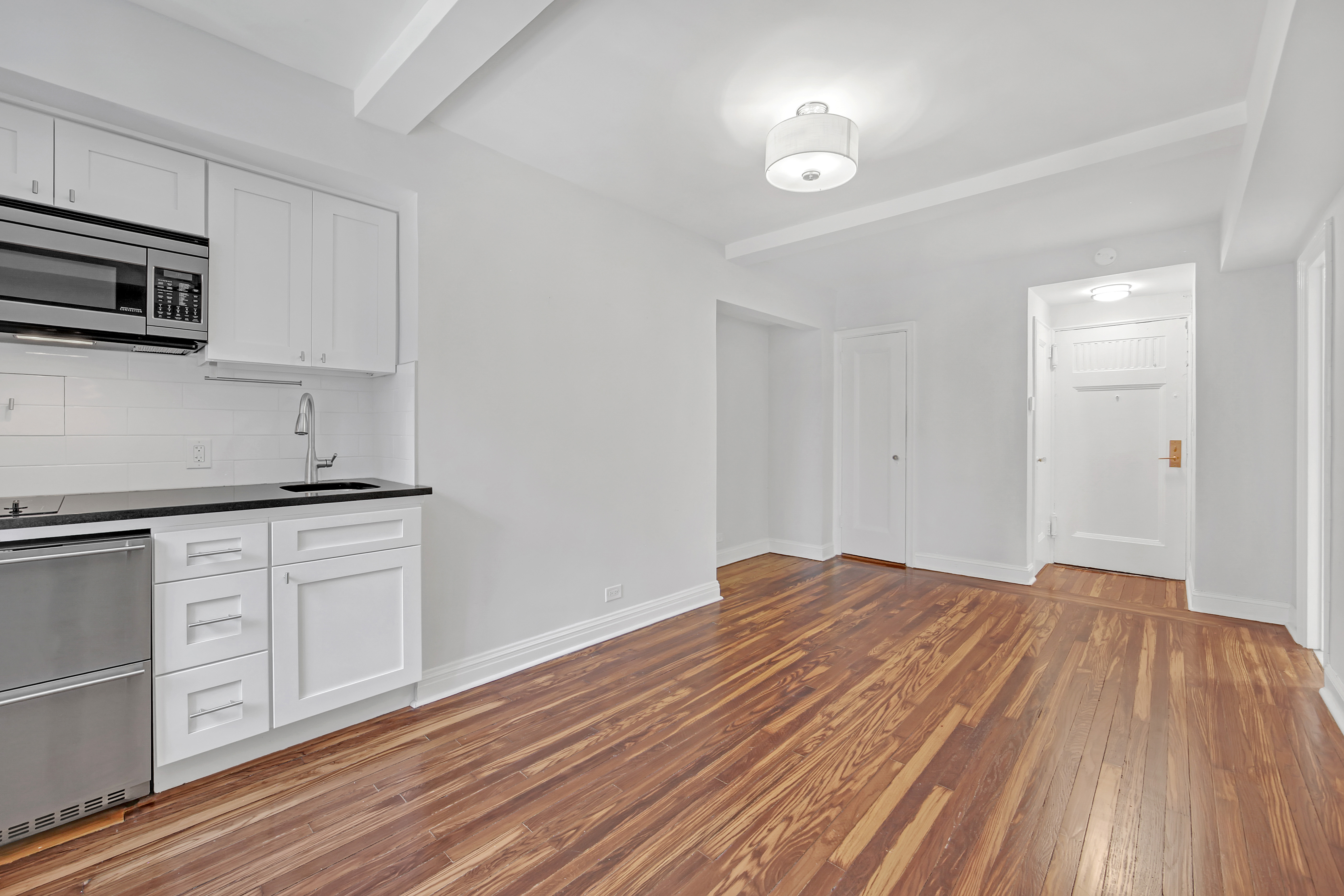 5 Tudor City Place, Unit 608 Manhattan, NY 10017 - Photo 6 of 12 a kitchen with stainless steel appliances granite countertop a dishwasher a stove and white cabinets with wooden floor
