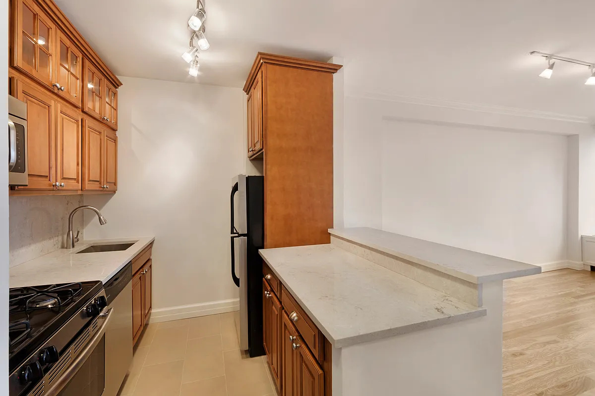 150 East 85th Street, Unit 11E Manhattan, NY 10028 - Photo 3 of 6 a kitchen with stainless steel appliances granite countertop a sink stove and refrigerator