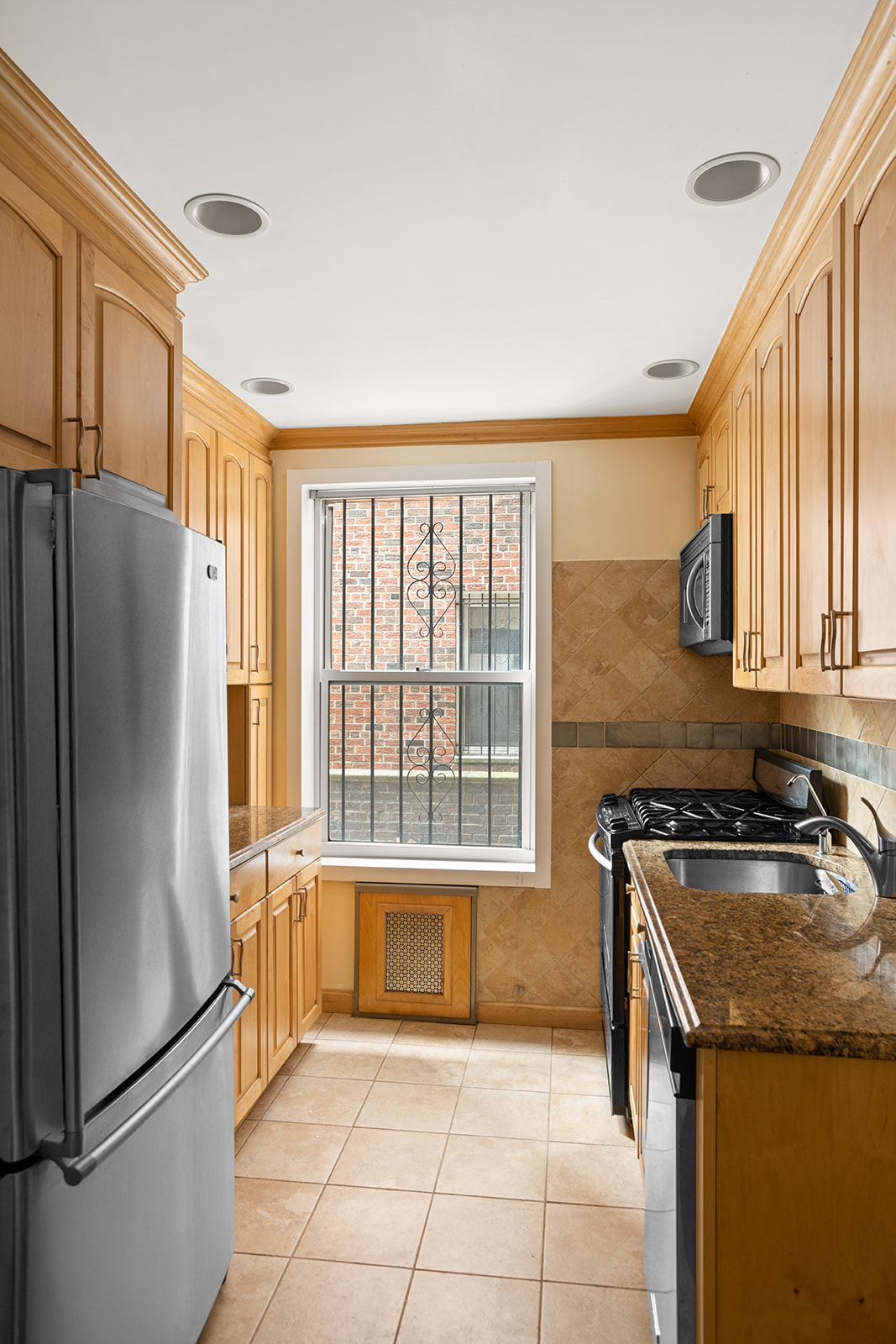 79-10 34th Avenue, Unit 2G Queens, NY 11372 - Photo 5 of 11 a kitchen with a refrigerator a sink and cabinets