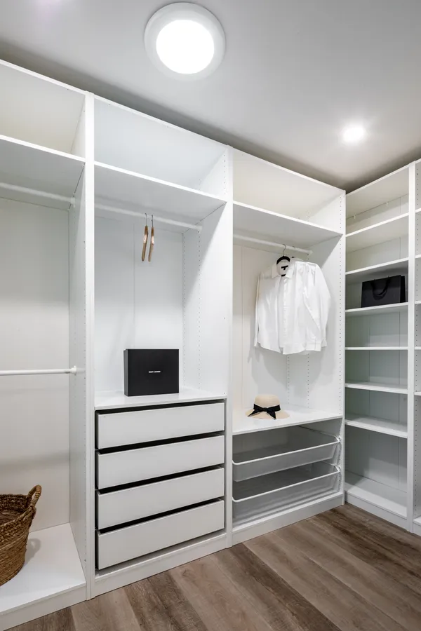 a white bedroom with a white bed and a closet