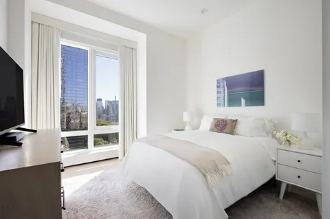 a bedroom with a bed and a flat tv screen on the dresser