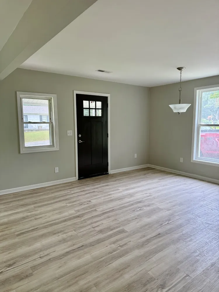 an empty room with wooden floor closet and windows