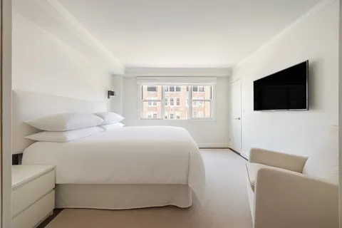 a bedroom with a bed a flat screen tv and a window