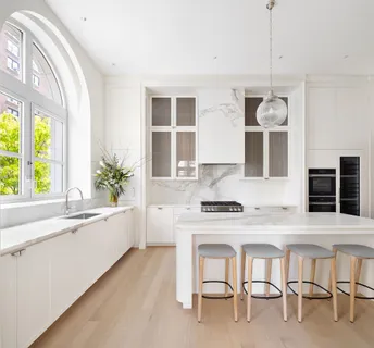 a kitchen with a stove a sink and white cabinets