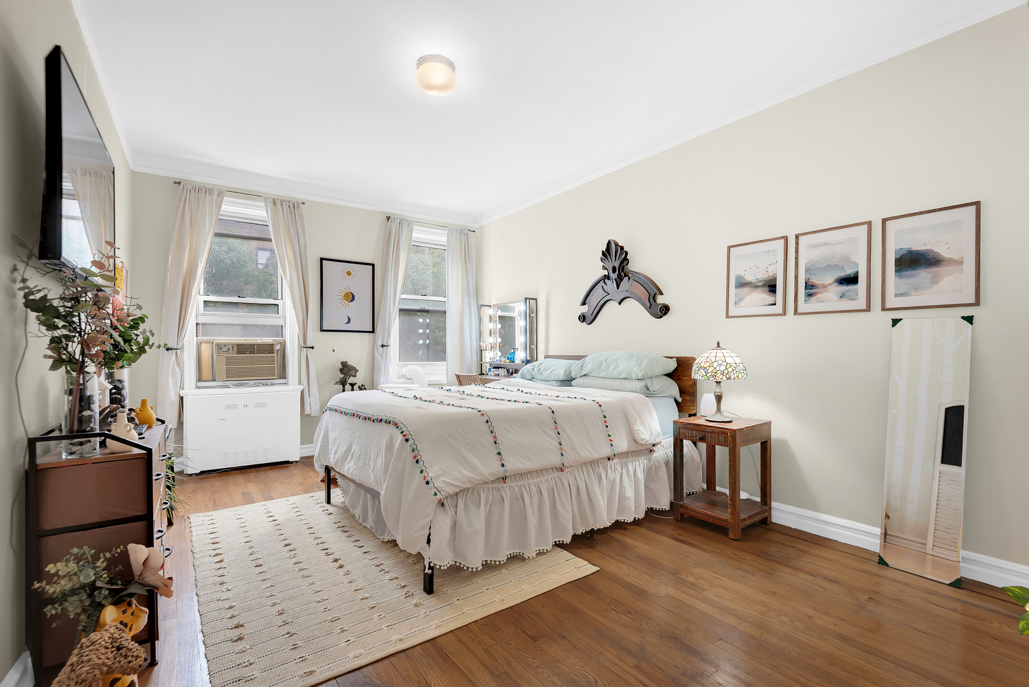 585 West 214th Street, Unit 4F Manhattan, NY 10034 - Photo 2 of 8 a bedroom with a large bed and a chandelier