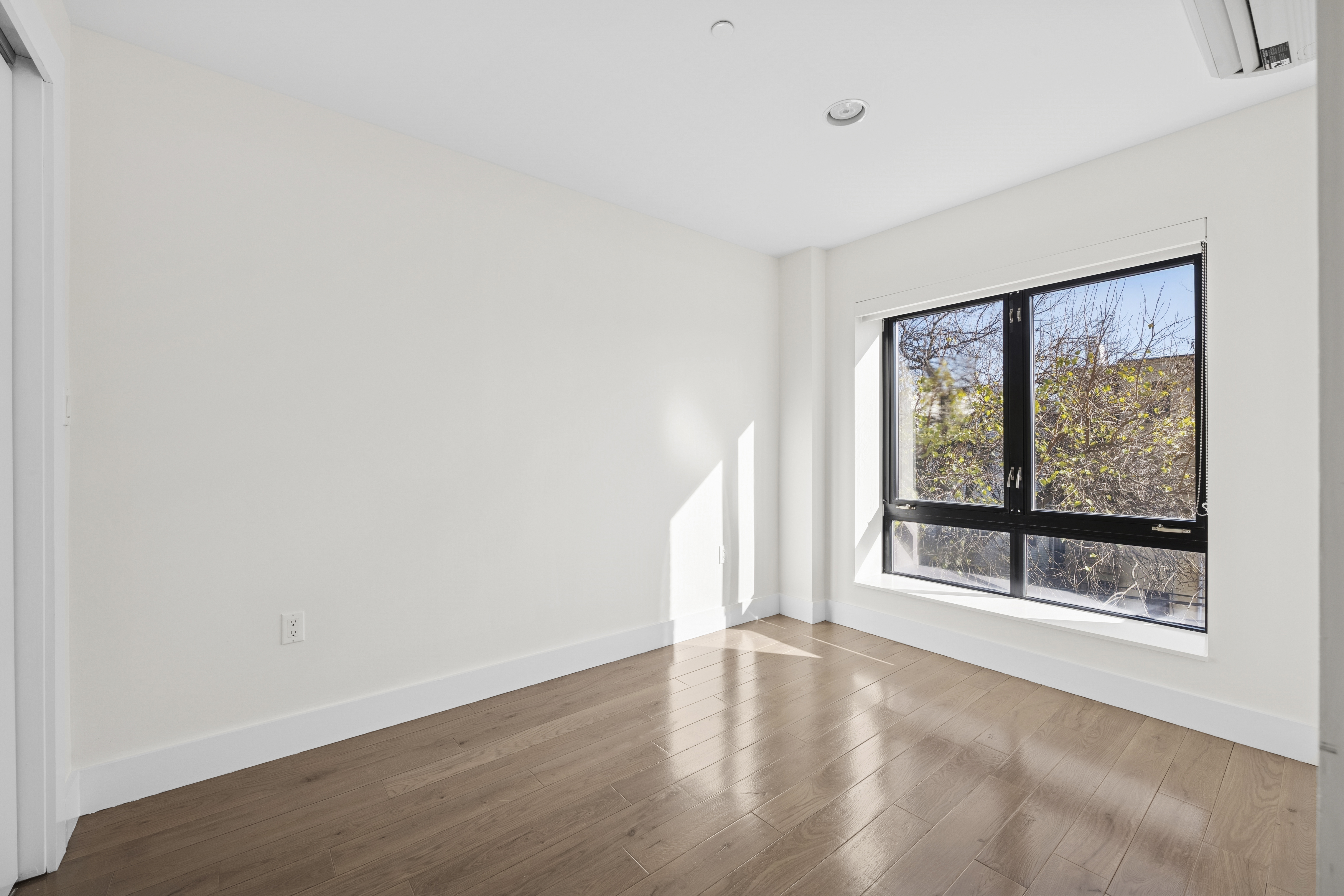 1164 Greene Avenue, Unit 3A Brooklyn, NY 11221 - Photo 5 of 11 an empty room with wooden floor and windows