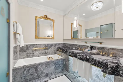 a bathroom with a granite countertop sink a large mirror and a bathtub