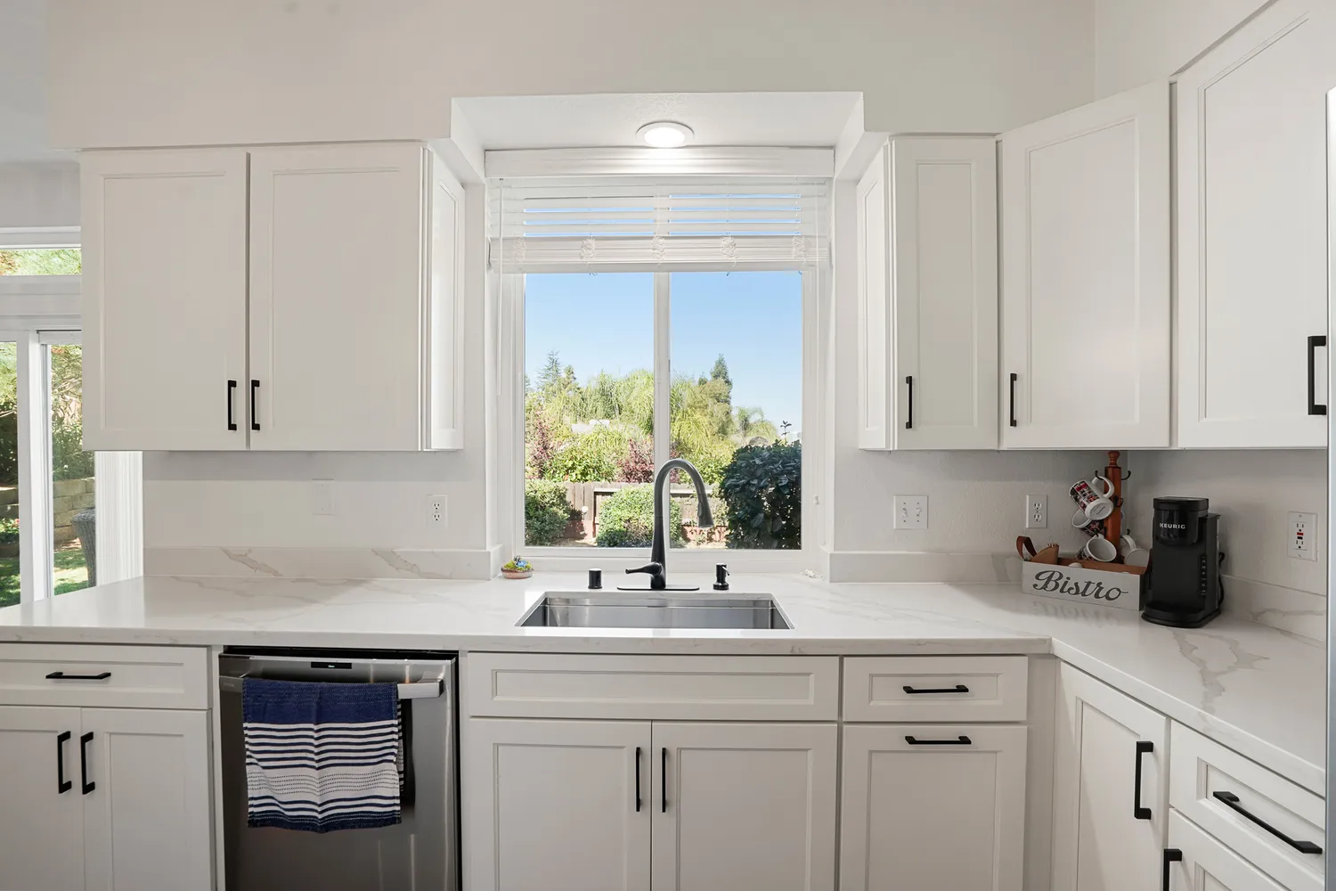 a kitchen with white cabinets and sink