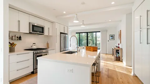 a kitchen with stainless steel appliances a stove top oven a sink a refrigerator and cabinets