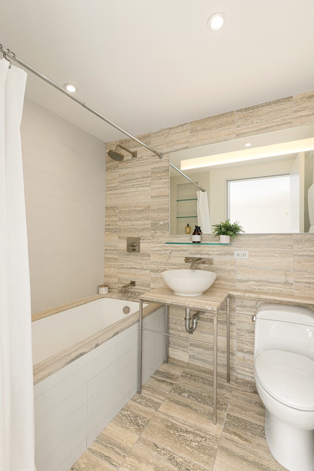 322 West 57th Street, Unit 23P Manhattan, NY 10019 - Photo 6 of 11 a bathroom with a sink a toilet a mirror and vanity