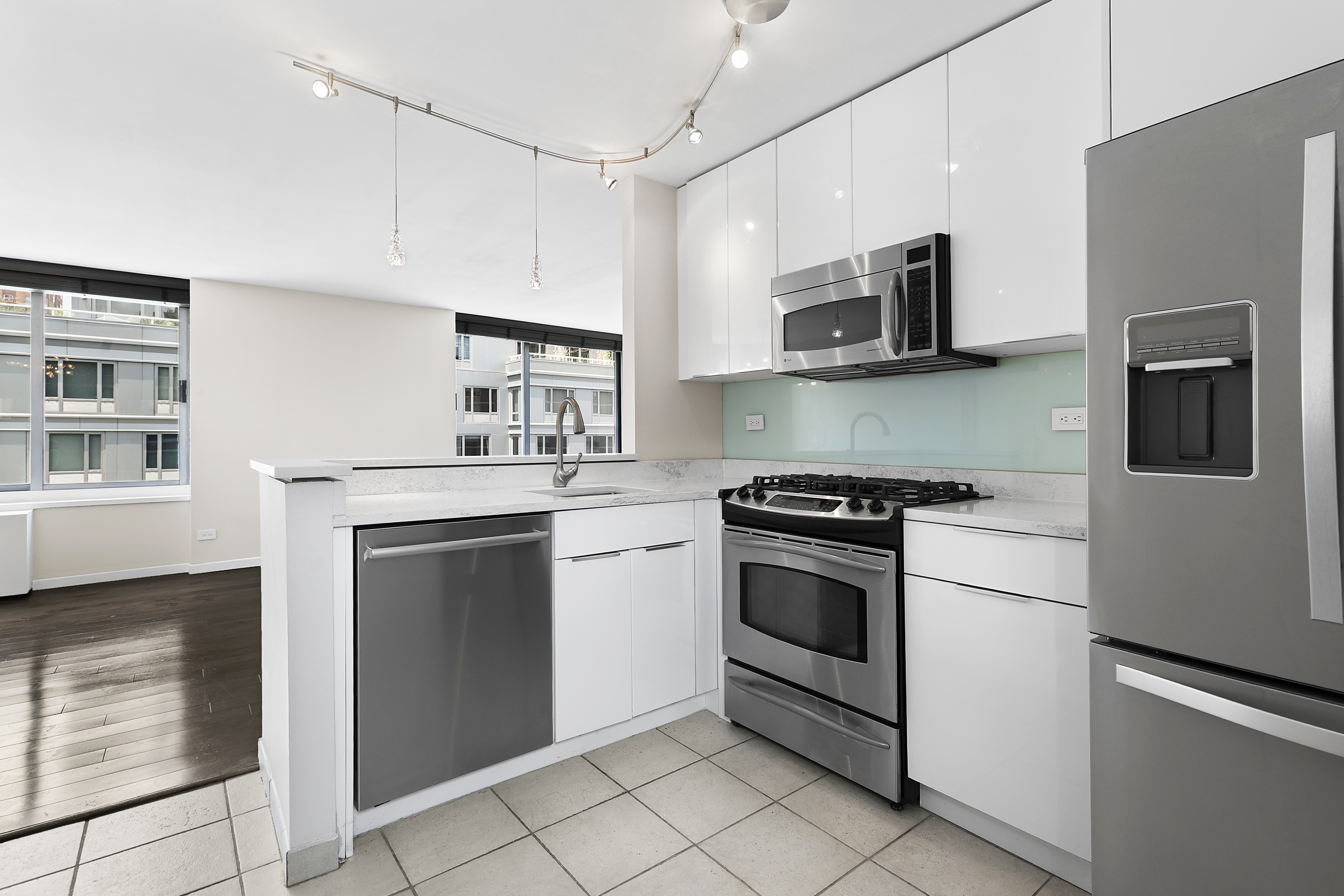 270 West 17th Street, Unit 4L Manhattan, NY 10011 - Photo 2 of 11 a kitchen with stainless steel appliances granite countertop white cabinets a sink a stove a microwave and a refrigerator