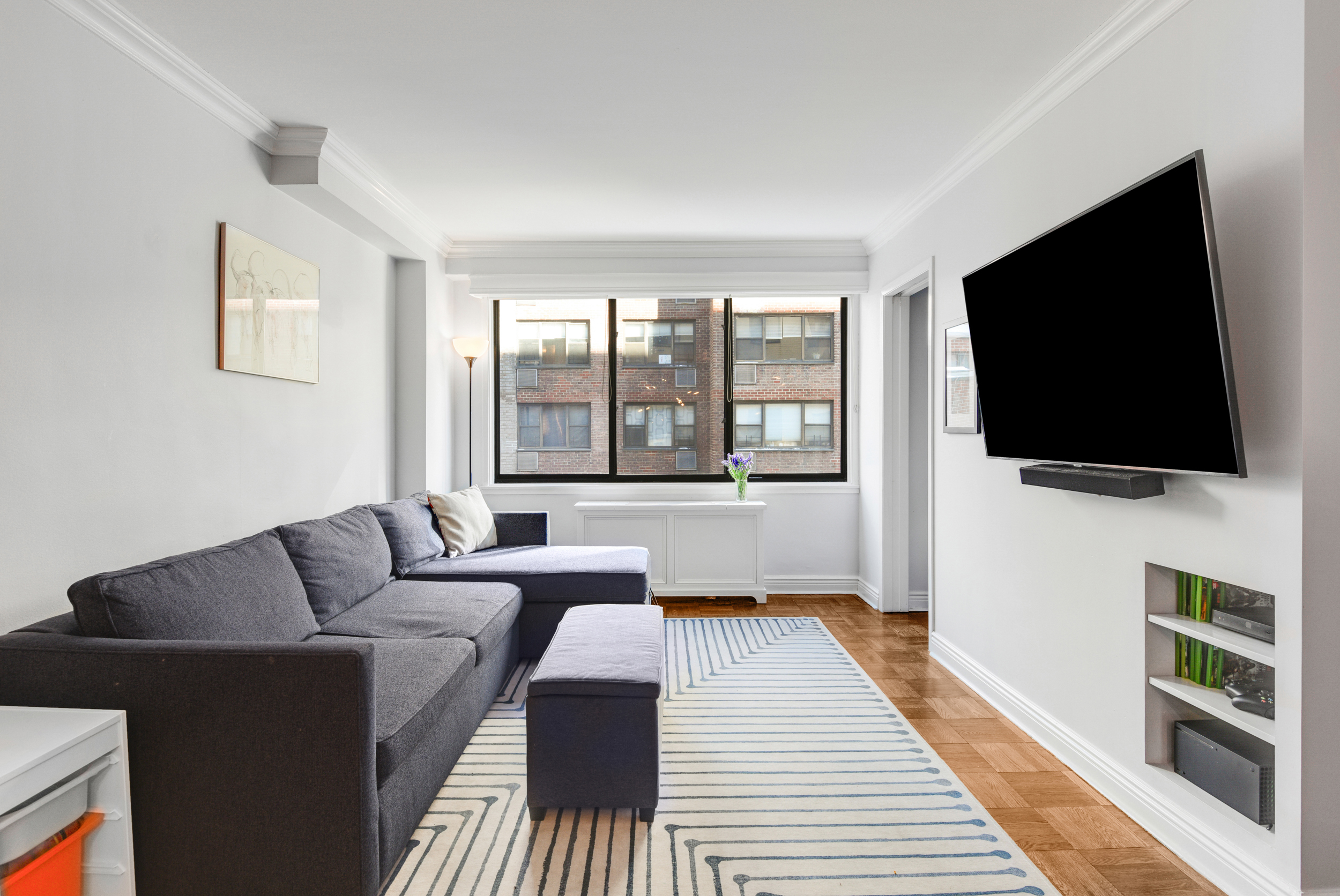 345 East 73rd Street, Unit 7J Manhattan, NY 10021 - Photo 2 of 13 a living room with furniture and a flat screen tv