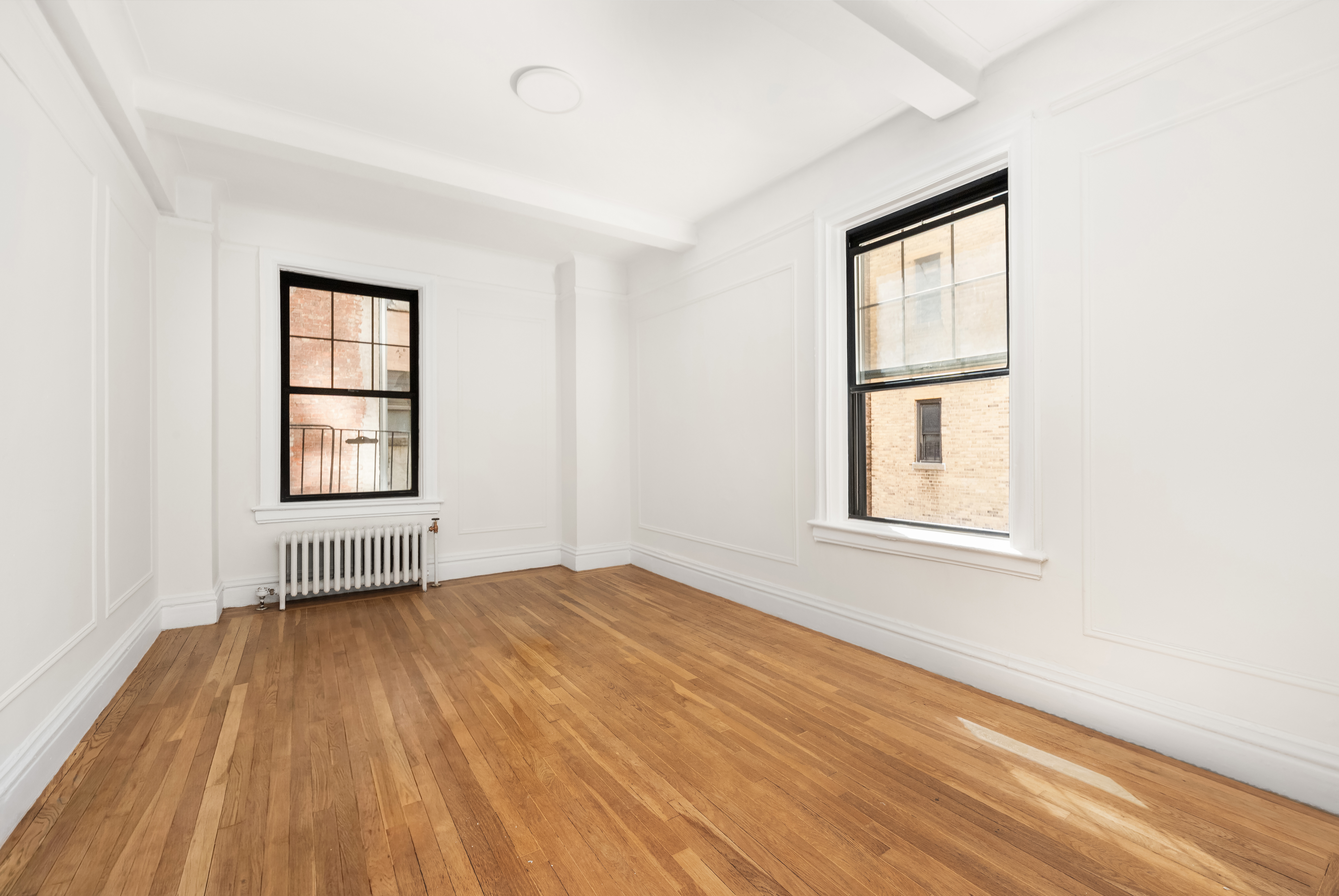 170 2nd Avenue, Unit 3E Manhattan, NY 10003 - Photo 4 of 12 an empty room with wooden floor and windows
