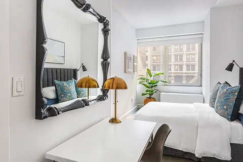 a bedroom with a bed mirror and window